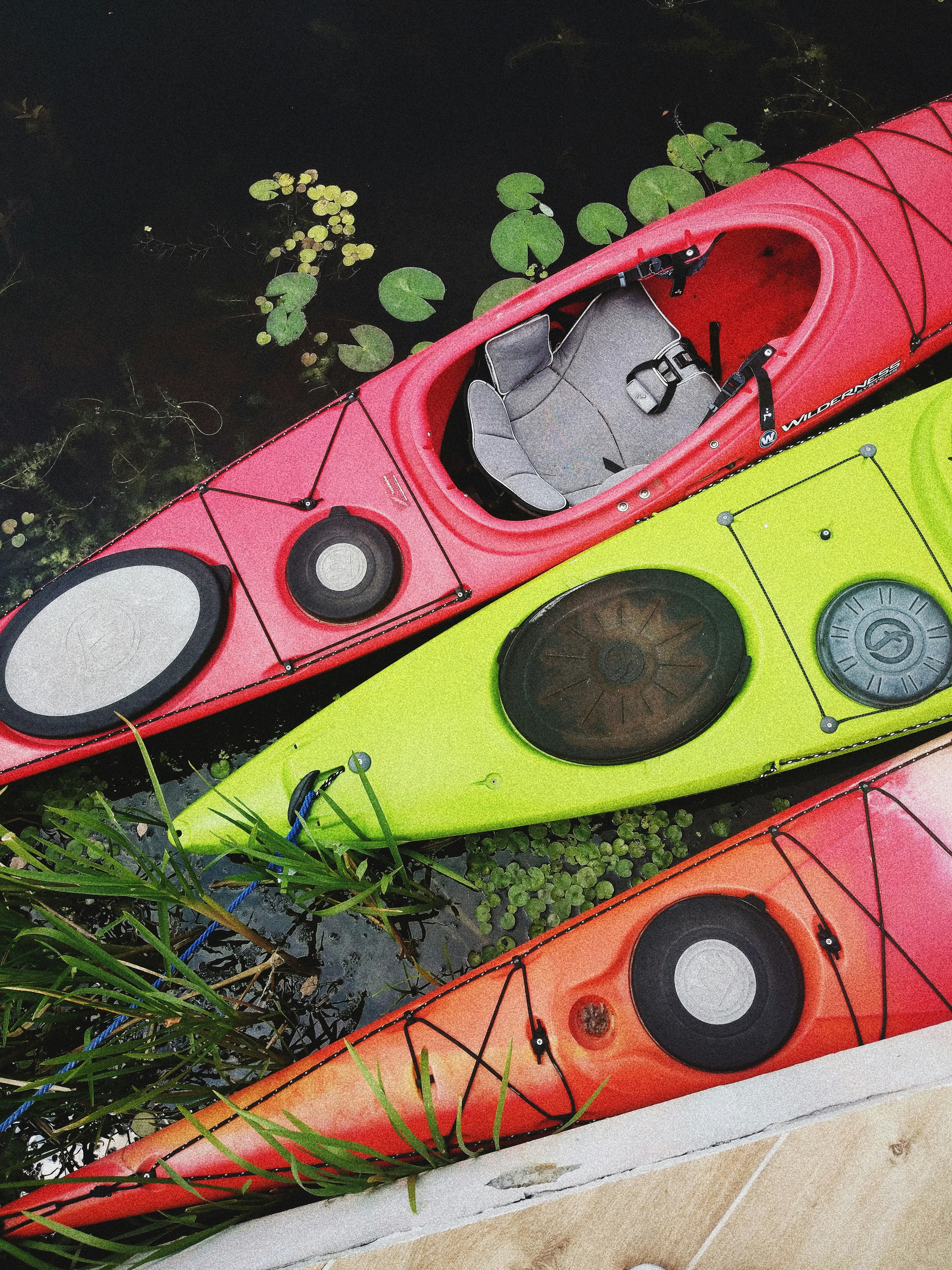 two red and one yellow kayaks on body of water